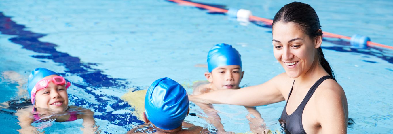 Monitora acompañando a un grupo de niños en la piscina de enseñanza